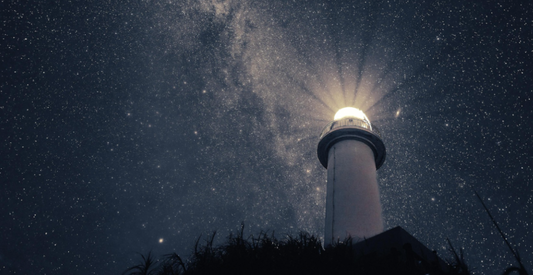 A lighthouse lighting up a starry night sky